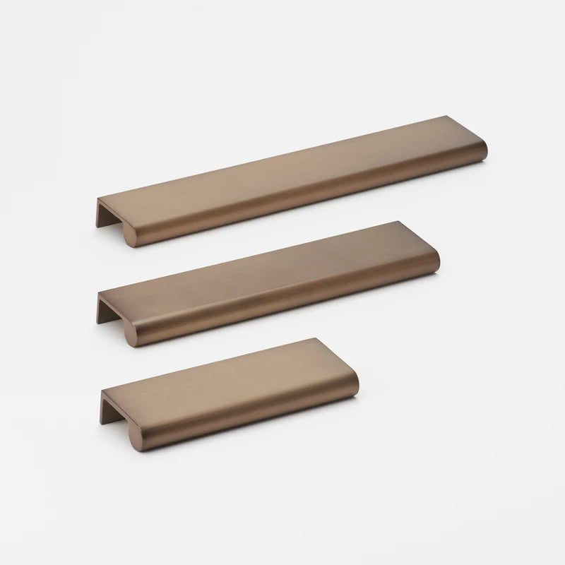 Brushed bronze Lo & Co Interiors Lincoln pull cabinet hardware with sleek modern design on a light wood cabinet.
