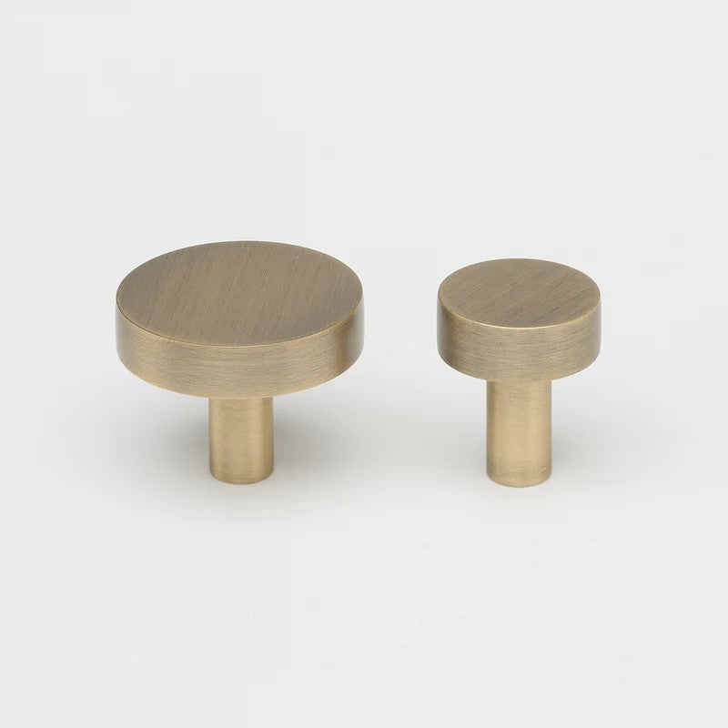 Lo & Co Ascot Knob cabinet hardware in antique brass finish, featuring a classic round design for furniture accents.