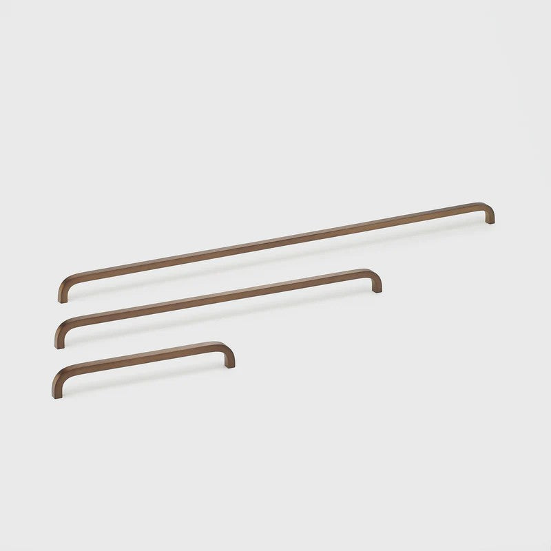 Lo & Co Interiors Curve Pull cabinet hardware in brushed bronze finish, featuring sleek, curved design for modern kitchen or furniture.