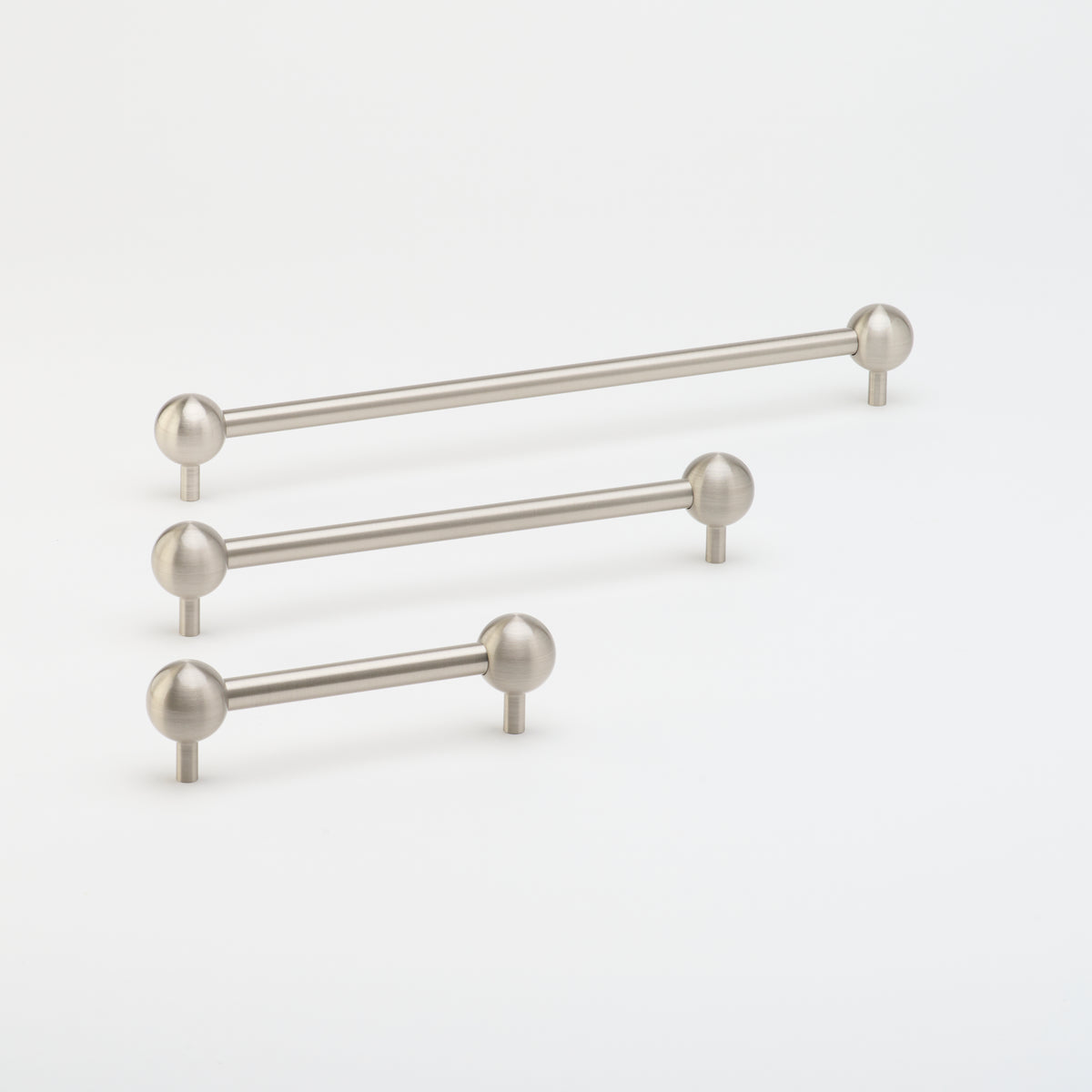 Brushed nickel Lo & Co Sphere Pull cabinet hardware mounted on a cabinet door, showcasing modern round design.