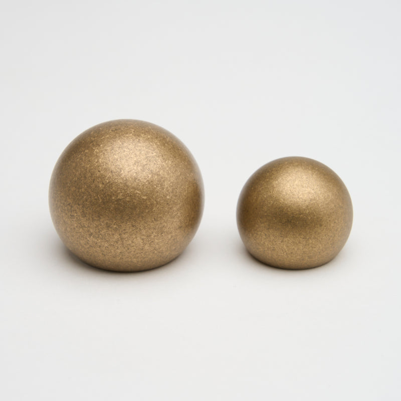 Brass Lo & Co Sphere Cabinet Knob with a polished finish, mounted on a cabinet door for a sleek, modern look.
