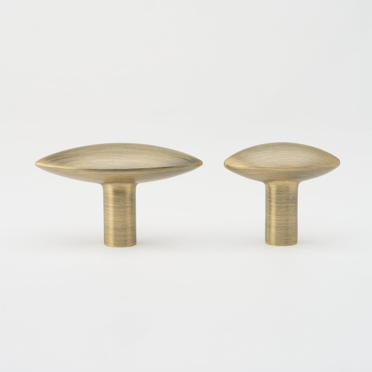 Lo & Co Almond Knob cabinet hardware in brushed brass finish, showing a close-up of the elegant, rounded design on a wooden cabinet door.