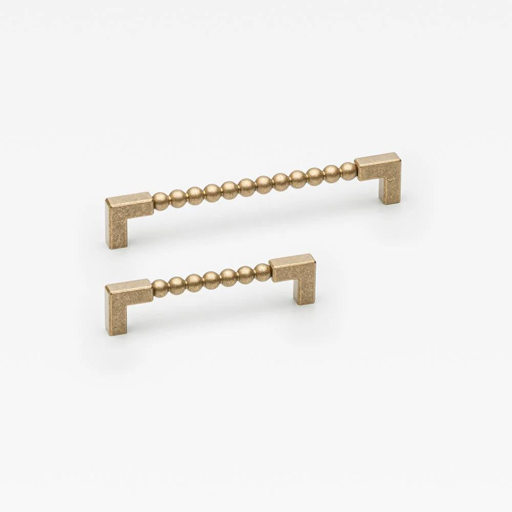 Small Lo & Co ORBE cabinet pull in brushed bronze, showcasing modern architectural hardware design on a cabinet.