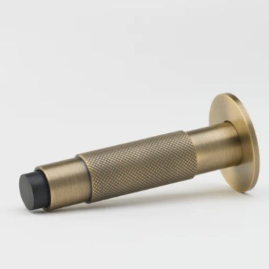 Lo & Co Interiors Knurled Kintore doorstop in brass finish, featuring textured knurled design and sturdy metal construction.