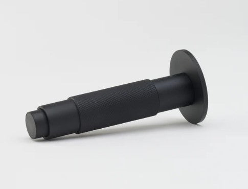 Lo & Co Interiors knurled Kintore doorstop in brushed metal finish, resting on a wooden floor.