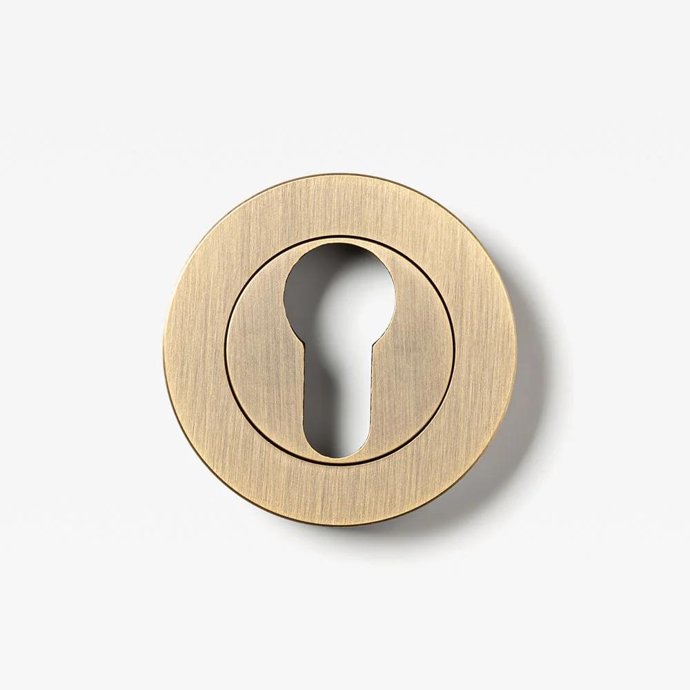 Round Euro cylinder escutcheon by Lo & Co Interiors, architectural hardware in brushed brass finish, designed for door security.