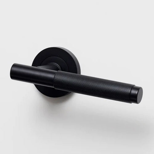Lo & Co Kintore knurled lever handle on a door, featuring a sleek metal finish and textured grip for modern interior design.