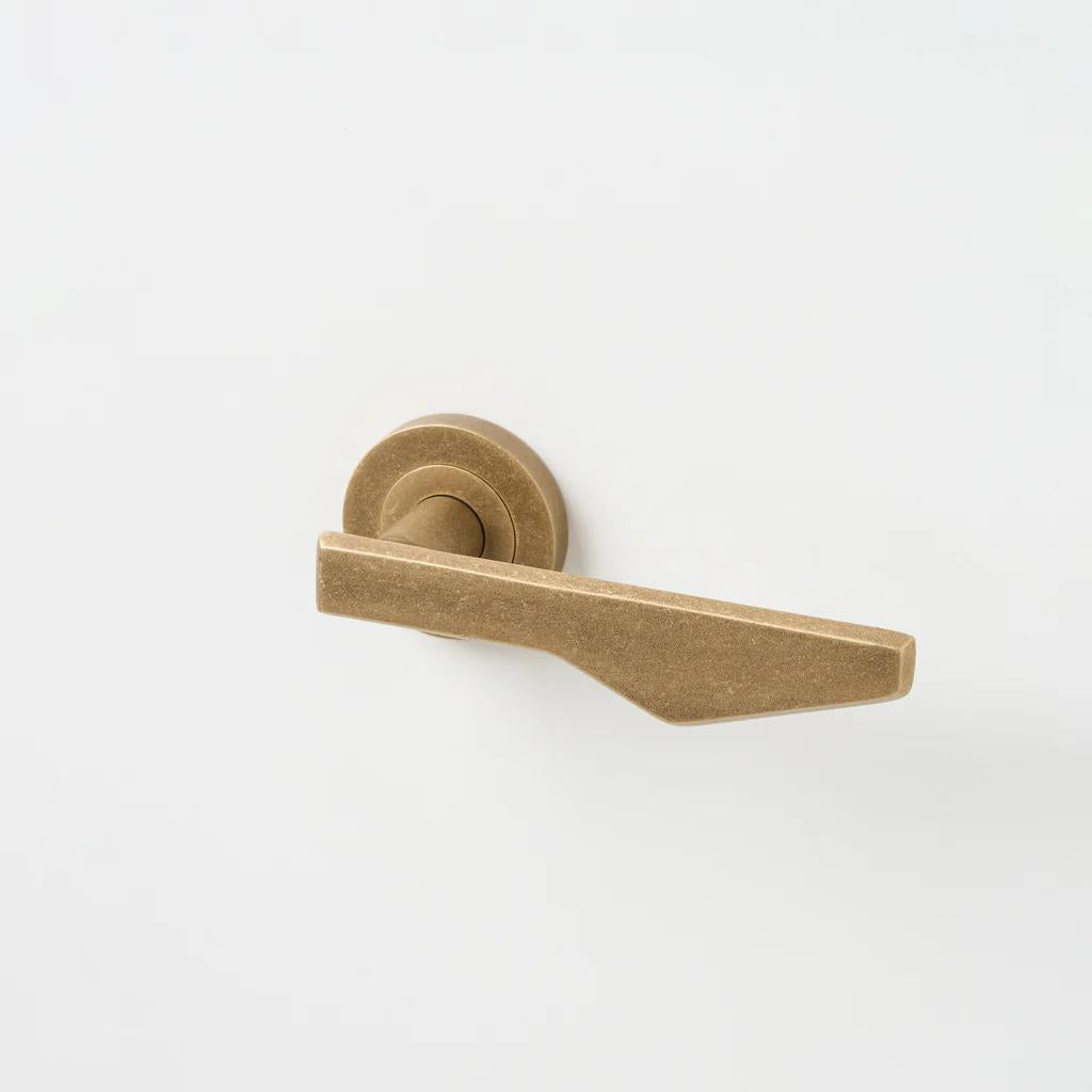 Lo & Co Interiors Outline C Lever door handle in bronze finish, showing the sleek, modern design on a door.