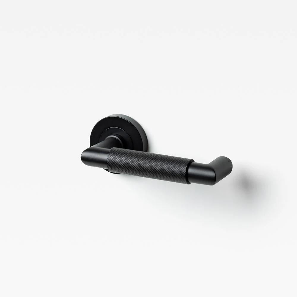 Lo & Co Kintore Knurled Return Lever in brass with knurled grip, shown on a door handle with a sleek, modern design.