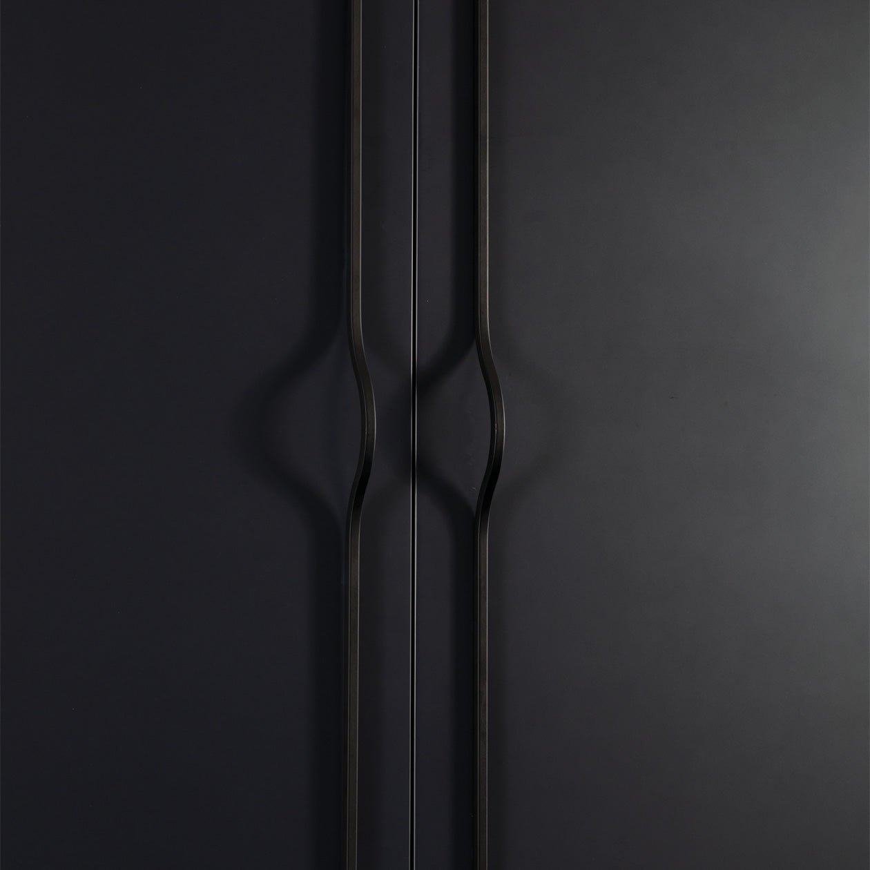 Momo BRAVE Bow Cabinet Pull Handles in black finish mounted on a cabinet door, showcasing sleek, curved design for kitchen or furniture.