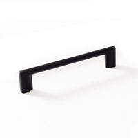 Momo BARRA D cabinet pull handle with a sleek metal finish, mounted on a wooden cabinet door for modern kitchen or furniture decor.
