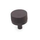 Momo Bellevue knurled cabinet knob in matte black with textured grip, mounted on a wooden cabinet door.