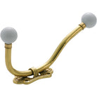Tradco traditional porcelain tip hat and coat hook mounted on wall, vintage-style metal hook with porcelain accents.