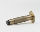 Lo & Co Interiors Knurled Kintore doorstop in brass finish, featuring textured knurled design and sturdy metal construction.