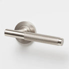 Lo & Co Kintore knurled lever handle in brushed nickel finish on a door, showcasing modern, textured design and sleek hardware.