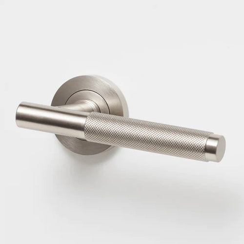 Lo & Co Kintore knurled lever handle in brushed nickel finish on a door, showcasing modern, textured design and sleek hardware.