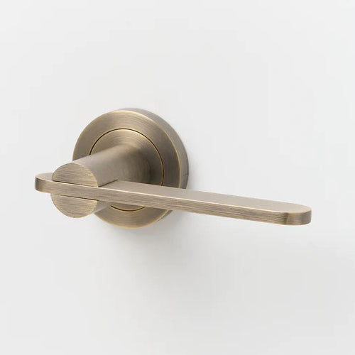 Lo & Co Intersect Lever door handle in brushed brass finish, showcasing a sleek modern design on a door.