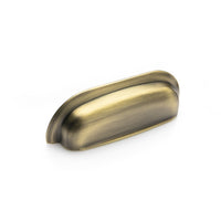 Momo New Hampton wide cup pull handle in dark bronze finish, showing its curved, wide grip design on a cabinet or furniture piece.
