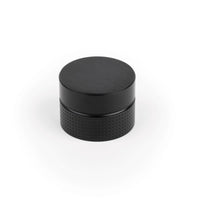 Momo POINT cabinet knob in black with a sleek, modern design, mounted on a wooden cabinet door.